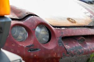 phares cassés à la suite d'une collision. voiture rouge cassée après un accident. notion d'accident de voiture. phare de secours, capot et pare-chocs endommagés. dommages à la carrosserie de la voiture après l'accident. photo