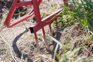 pelle rouge en forme de fourchette dans le jardin. pelle miracle, outil pratique. cultivateur manuel. le cultivateur est un outil efficace pour le travail du sol. relâchement du lit. outils agricoles durables. photo