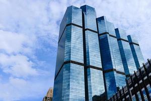 ciel bleu et nuages reflétés sur le verre des immeubles de bureaux dans le centre-ville par une belle journée ensoleillée. photo