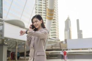 une belle jeune femme d'affaires utilise un téléphone intelligent dans la ville moderne, la technologie d'entreprise, le concept de style de vie urbain photo