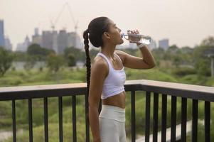 jeune femme de remise en forme en vêtements de sport buvant de l'eau dans le parc de la ville, des modes de vie sains et sains.