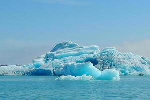 iceberg bleu clair brillant flottant dans l'eau froide bleue du lac jokulsarlon en islande 3 photo