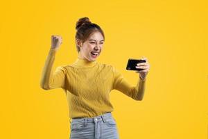 portrait d'une belle femme asiatique dans une chemise jaune jouant sur un smartphone. concept de portrait utilisé pour la publicité et la signalisation, isolé sur fond blanc, espace de copie. photo