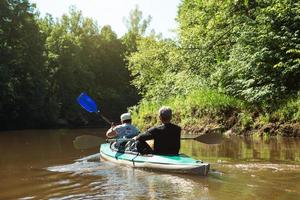 balade en kayak en famille. un couple marié âgé ramant un bateau sur la rivière, une randonnée aquatique, une aventure estivale. sports liés à l'âge, jeunesse et santé mentale, tourisme, vieillesse active photo