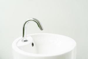 lavabo hygiénique avec robinet chromé sur fond de fenêtre de salle de bain. lavabo blanc pour se laver les mains photo