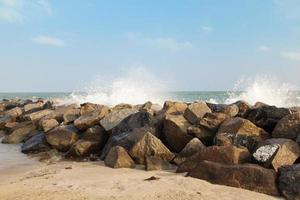 côte rocheuse avec de longues vagues clapotant avec du sable et du ciel bleu. photo