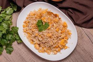 riz frit aux œufs de cuisine thaïlandaise dans une assiette blanche sur un plancher en bois photo