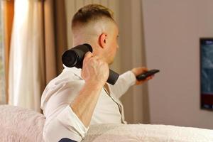 homme avec un pistolet de massage devant la télé photo