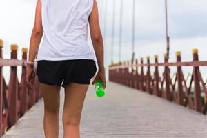 exercice de femme marchant sur le pont avec une bouteille d'eau à la main. photo