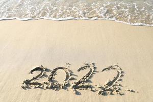 numéros 2022 ans sur le bord de la mer, écrits à la main dans le sable sur fond de plage. photo