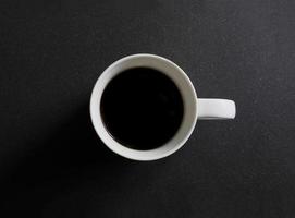 vue de dessus d'une tasse de café blanche sur un comptoir en granit noir photo