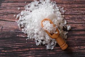 fleur de sel, est un sel qui se forme comme une fine croûte délicate à la surface de l'eau de mer dans la cuillère en bois sur fond de bois. photo