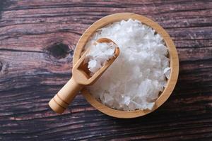 fleur de sel, est un sel qui se forme comme une fine croûte délicate à la surface de l'eau de mer dans la cuillère en bois et le bol en bois sur fond de bois. mise au point sélective. photo