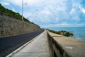 destination idéale pour un road trip au coucher du soleil sur une île du vietnam. long hai côtier panoramique avec vagues, littoral, ciel clair et route, mer bleue et montagne. photo