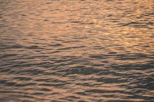 l'eau du coucher du soleil reflète les ondulations à la lumière du soleil. réflexion dorée abstraite sur le coucher du soleil sur l'eau photo