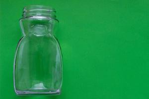 bouteille vide en verre transparent sur fond vert avec place pour votre conception. photo