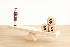 concept d'équilibre vie-travail ou argent. figurine de femme d'affaires et symbole du dollar sur des blocs de bois sur une balançoire en bois photo