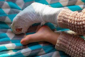 enfant avec bandage sur fracture du talon de la jambe. pied droit cassé, attelle de bambin. petit boi dormant sur une couverture bleue. photo