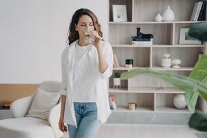 jolie femme espagnole boit de l'eau propre à la maison. eau purifiée pour un mode de vie sain. photo