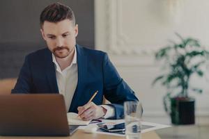 jeune beau directeur exécutif travaillant devant un ordinateur portable au bureau à domicile photo