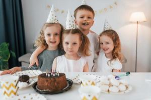 posant pour la caméra. célébrer l'anniversaire. groupe d'enfants est ensemble à la maison pendant la journée photo