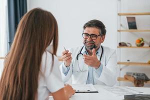 médecin de sexe masculin donnant des consultations à la femme. travailleur médical professionnel en blouse blanche est au bureau photo