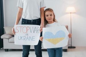 mère avec sa petite fille debout avec des bannières avec texte arrêter la guerre en ukrane photo