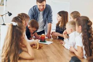 regardant le petit modèle de volcan. groupe d'enfants élèves en classe à l'école avec professeur photo