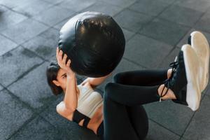 ballon de fitness noir. femme en vêtements sportifs avec un type de corps mince est dans la salle de gym photo