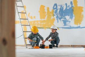 fond de couleur bleu et jaune. deux garçons peignant des murs dans la chambre domestique photo