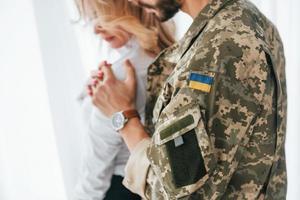 drapeau ukrainien. soldat avec sa femme debout à l'intérieur et embrassant photo