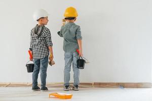 vue arrière. deux garçons peignant des murs dans la chambre domestique photo