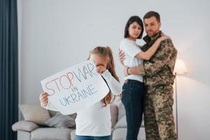 arrêter la guerre dans la conception ukrainienne. soldat en uniforme est à la maison avec sa femme et sa fille photo