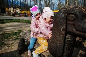 deux sœurs sont assises dans un animal en bois au zoo. photo