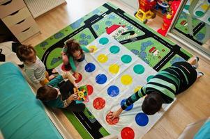 famille heureuse s'amusant ensemble, quatre enfants jouant au jeu twister à la maison. photo