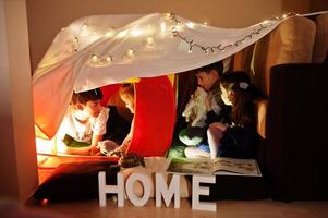 jouer aux enfants avec le chat dans la tente la nuit à la maison. humeur hygge. photo