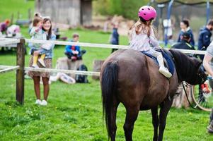 petite petite fille en poney de tour de casque rose. photo