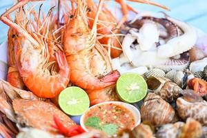 Assiette de fruits de mer avec crevettes coquillages crabe calmar coque babylone tachetée avec sauce aux fruits de mer chili citron citron vert servir sur la table à manger, crevettes crevettes menu buffet de fruits de mer plats cuisinés photo