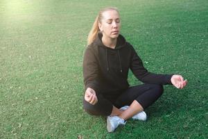 belle femme d'âge moyen assise sur une herbe en yoga asana photo