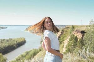 jolie femme d'âge moyen se dresse sur une haute rive du fleuve photo