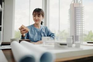 mise au point sélective, architecte ou ingénieure asiatique envisageant actuellement des matériaux pour la conception de condominiums modernes. femme architecte ou ingénieure asiatique s'asseoir et analyser, concevoir des projets au bureau photo