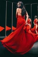 portrait d'une belle femme brune en chaussures et robe rouges se retournant et dansant près des miroirs photo