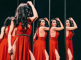 portrait d'une belle femme brune en chaussures rouges et robe debout près des miroirs