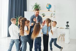 geste de high fives. groupe d'enfants élèves en classe à l'école avec professeur photo