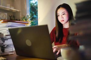 femme d'affaires asiatique travaillant sur un ordinateur portable au bureau à domicile. faire des heures supplémentaires photo