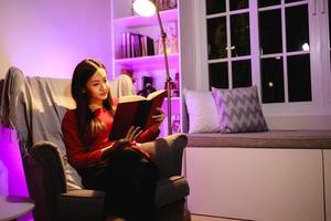 jeune femme lisant un roman historique préféré sur un fauteuil. concept de loisirs et de personnes photo