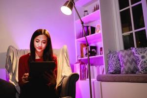 Asain belle femme à l'aide d'une tablette numérique à la maison pendant la nuit photo