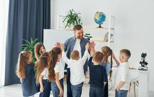 debout et donnant des high fives. groupe d'enfants élèves en classe à l'école avec professeur photo
