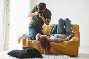 ne bouge pas. photographe prenant une photo d'une jeune fille allongée sur le canapé blanc