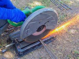 la main du travailleur coupant la tige d'acier par une machine sur le chantier de construction photo